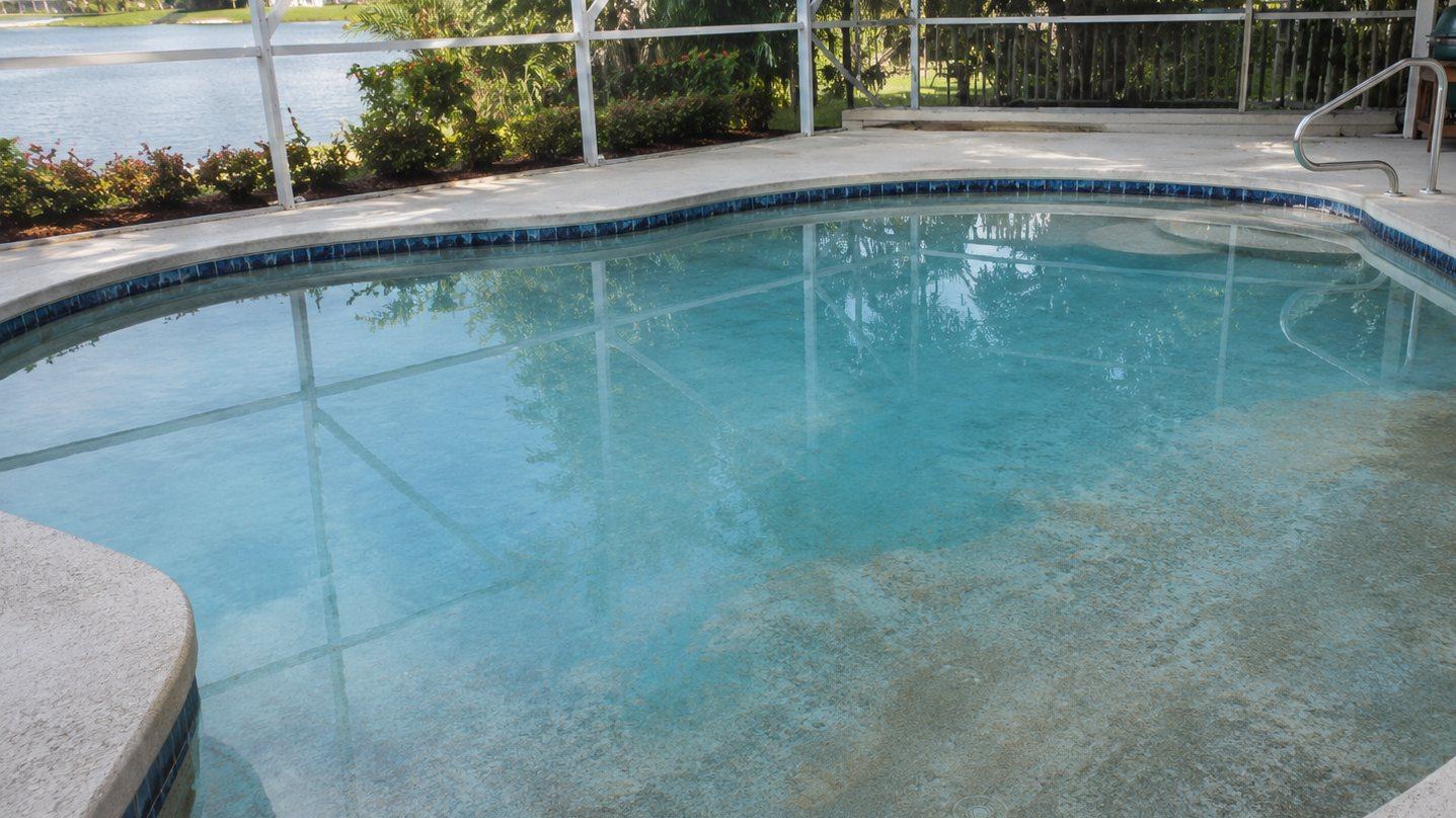 A residential pool in Cape Coral showing an aged, discolored plaster surface typical of older Florida pools